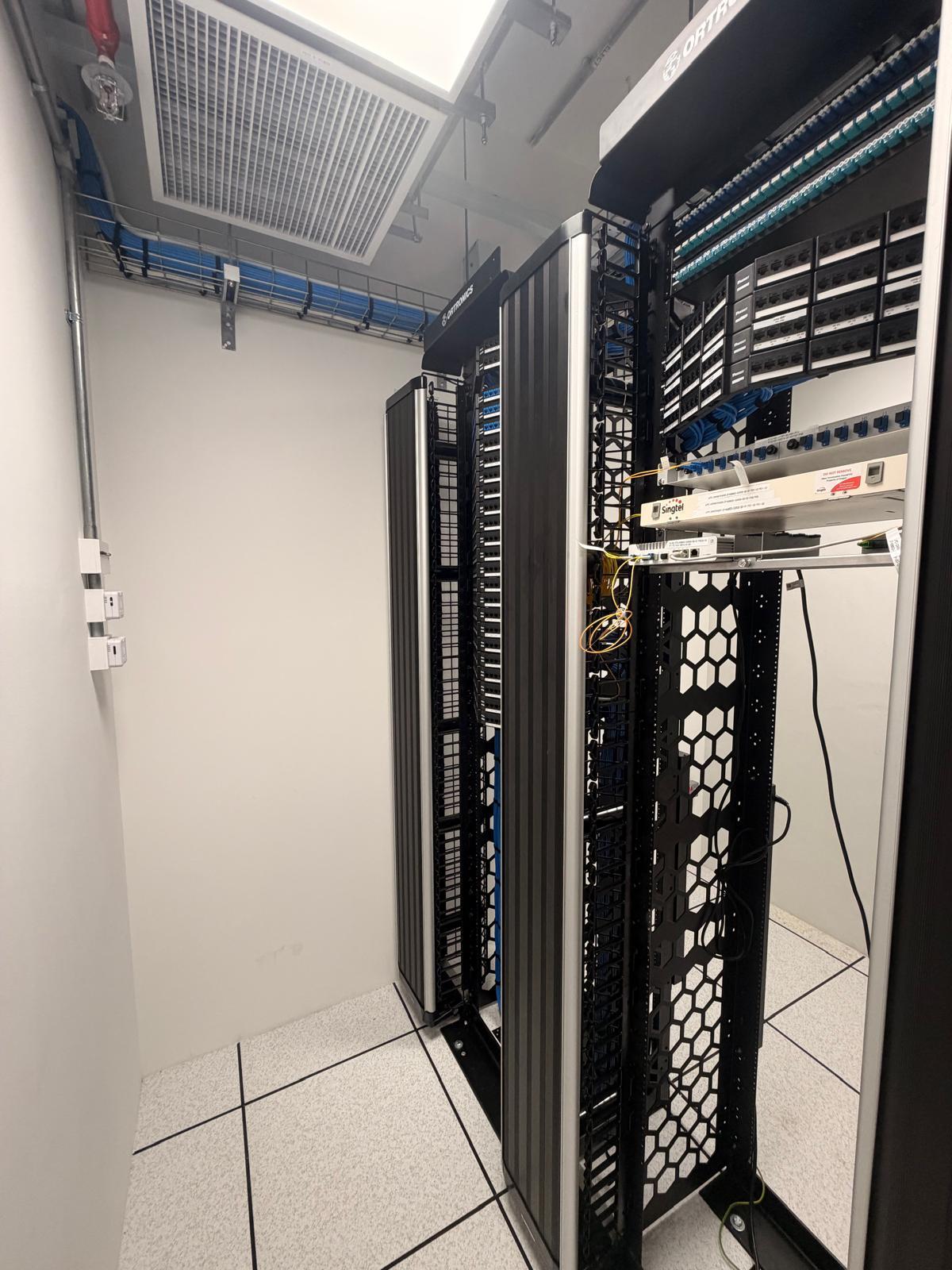 Structured cabling racks with Cat6 patch panels, fibre trays and Singtel termination in a Singapore server room
