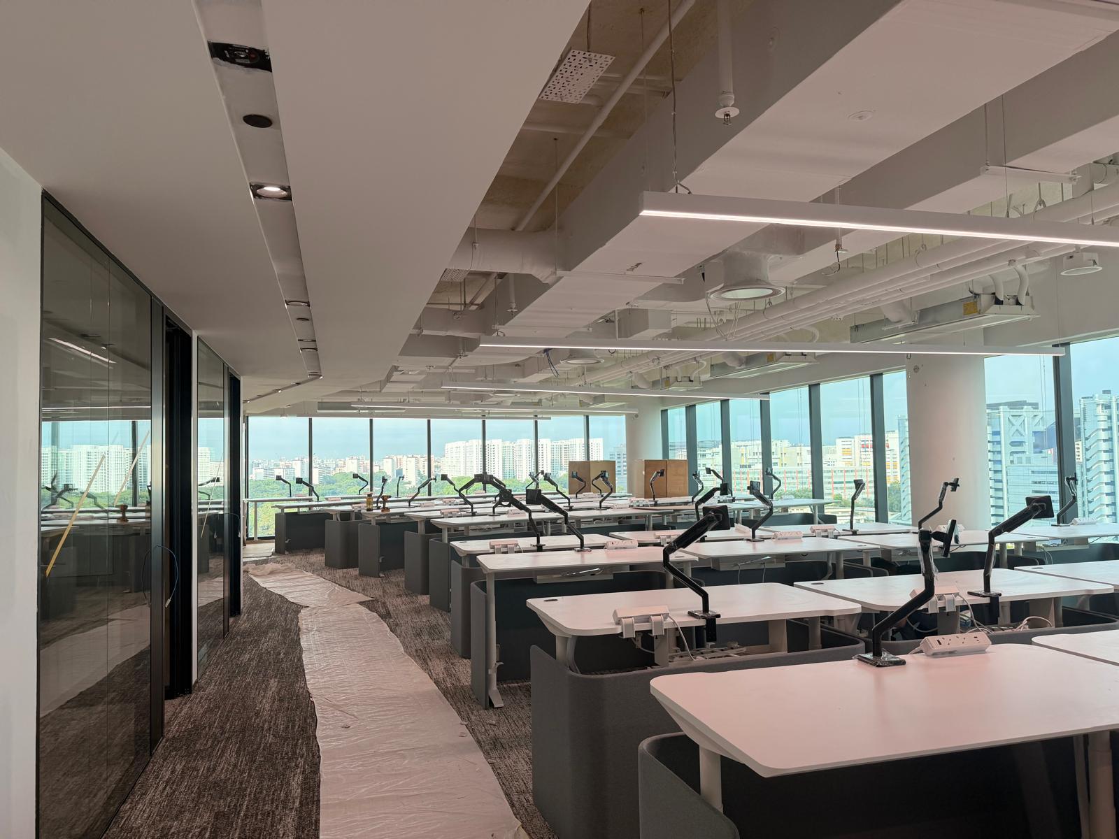 Open plan office desks with floor power sockets, data points, monitor arms and linear lighting — Singapore office fit-out